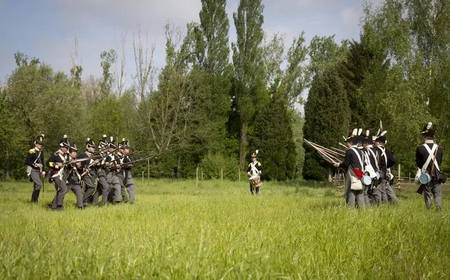 In this May 10, 2015, photo, historical re-enactors dressed as soldiers of the Belgian-Dutch 7th Battalion of the Line face off against each other in a mock battle at a Napoleonic era living history camp in Elewijt, Belgium. The Belgian-Dutch living history group is coordinating their group for participation in the 200th anniversary of the Battle of Waterloo which will take place in June 2015. (AP Photo/Virginia Mayo)