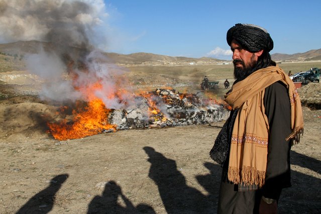 A Taliban Security personnel stands guard while authorities burn drugs and alcoholic drinks on the outskirts of Ghazni province on May 5, 2024. (Photo by Mohammad Faisal Naweed/AFP Photo)