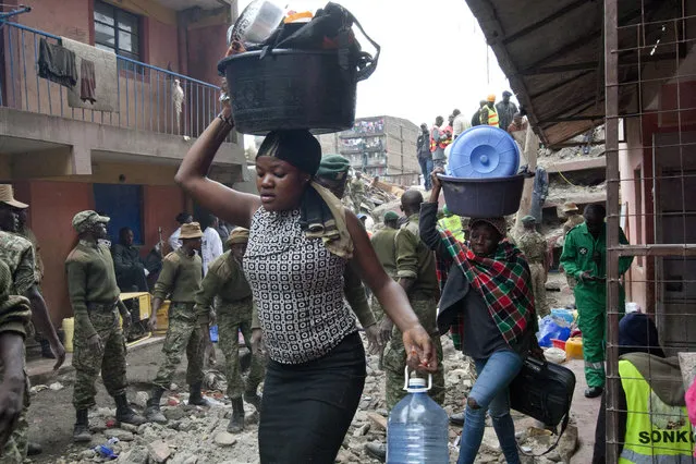 Survivors carry their belongings at the site of a building collapse in Nairobi, Kenya, Saturday, April 30, 2016. (Photo by Sayyid Abdul Azim/AP Photo)