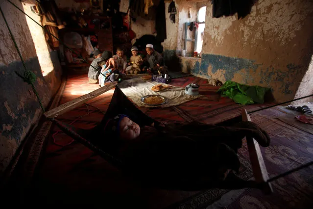 An ethnic Hazara child sleeps as the rest of the family eat a meal in their home in Turkman camp in Nowshera, Pakistan February 9, 2017. (Photo by Fayaz Aziz/Reuters)