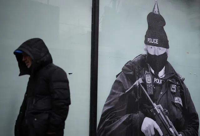 A photo-montage of British Prime Minister Boris Johnson created by the anonymous street artist “Foka Wolf” is displayed on a shop window on February 14, 2022 in Manchester, England. The mural depicts Boris Johnson dressed as an armed policeman wearing a party hat and is displayed on the windows of the former Debenhams store on Market Street, Manchester. (Photo by Christopher Furlong/Getty Images)