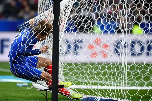 France's forward Antoine Griezmann falls into the net of the goal during the friendly football match France vs Spain on March 28, 2017 at the Stade de France stadium in Saint-Denis, north of Paris. Spain won the match 0–2. (Photo by Franck Fife/AFP Photo)