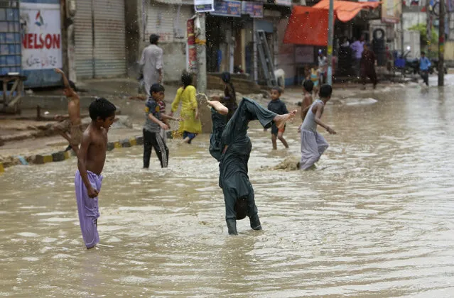 Pakistani boys play in a flooded street after a heavy rainfall in Karachi, Pakistan, Monday, July 29, 2019. The Pakistan Meteorological Department said that a rain system entered Sindh province from India's Rajasthan and forecasts another three days of rain. (Photo by Fareed Khan/AP Photo)