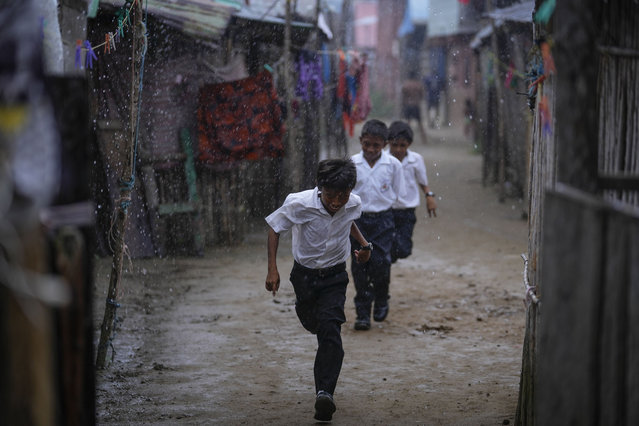Children run to school in the rain in Gardi Sugdub Island, part of the San Blas archipelago off Panama's Caribbean coast, Monday, May 27, 2024. Due to rising sea levels, about 300 Guna Indigenous families will relocate to new homes, built by the government, on the mainland. (Photo by Matias Delacroix/AP Photo)
