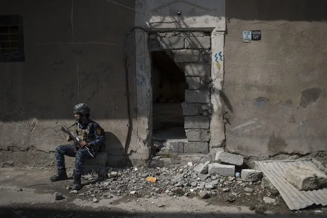 A federal policeman takes a break from inspecting houses during fighting against Islamic State militants on the western side of Mosul, Iraq, Wednesday, March 29, 2017. (Photo by Felipe Dana/AP Photo)