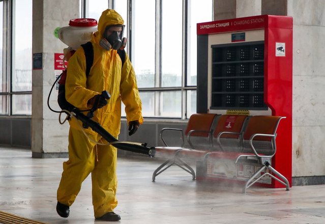 An employee of the Lider Center for Special Risk Rescue Operations of Russia's Emergencies Ministry carries out disinfection of the Belorussky railway station and surrounding grounds amid the ongoing COVID-19 coronavirus pandemic in Moscow, Russia on June 11, 2021. (Photo by Anton Novoderezhkin/TASS)