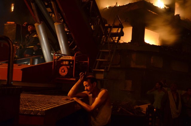 A man rests near a fire engine as firefighters try to extinguish a fire that engulfed several buildings in Cairo, Egypt, 09 May 2016. According to reports, 50 people were injured, including firefighters, when an overnight fire at a small hotel in Ataba neighborhood spread to other buildings and markets in the old area of Cairo. (Photo by Ayman Aref/EPA)
