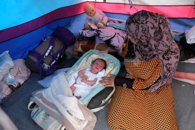 A woman sits by Yasmin, a twenty-day-old baby in her tent at a makeshift camp for migrants and refugees at the Greek-Macedonian border near the village of Idomeni, Greece, May 10, 2016. (Photo by Marko Djurica/Reuters)