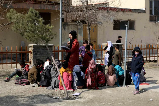 Afghan children take free classes provided by an Afghan woman Soda Najhand, a high school graduate, for children working as street vendors in Kabul, Afghanistan, 20 February 2022 (issued 22 February 2022). Many of these children work and have been denied an education owing to financial difficulties. Sodaba offered free schooling to these street children in a park so that these students are not left behind in their schooling as they express a strong desire to learn for a better future. The class for about 30 students takes three hours a day. (Photo by EPA/EFE/Stringer)
