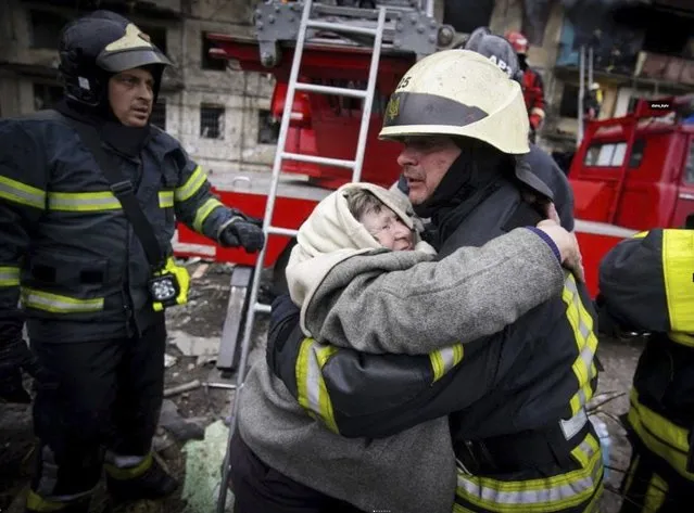 In this photo released by Ukrainian State Emergency Service, a firefighter hugs an elderly woman after evacuation from an apartment building hit by shelling in Kyiv, Ukraine, Monday, March 14, 2022. (Photo by Ukrainian State Emergency Service via AP Photo)