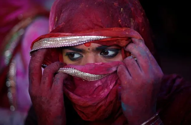 A girl covers her face as she takes part in the religious festival of Holi inside a temple in Nandgaon village, in the state of Uttar Pradesh, India, March 12, 2022. (Photo by Adnan Abidi/Reuters)