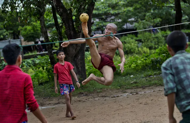 In this Sunday, Sept. 29, 2013 photo, an airborne Buddhist monk kicks a rattan ball during a game of Chinlone in Kawhmu, Myanmar, southwest of Yangon. A combination of sport and dance, it is played between two teams of six players each, passing the ball back and forth with their feet, knees or heads. (Photo by Gemunu Amarasinghe/AP Photo)