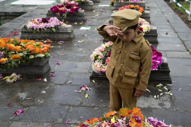 A Kashmiri Muslim boy dressed in a police uniform salutes after offering flowers at the Martyr's Graveyard in Srinagar, Indian controlled Kashmir, Monday, July 13, 2015. Parts of Indian-controlled Kashmir remained under curfew to stop a rally by separatist groups in memory of the day in 1931 when the region's Hindu king ordered more than 20 Kashmiri Muslims executed in a bid to put down an uprising. July 13 is observed as Martyrs' Day in the state. (Photo by Dar Yasin/AP Photo)