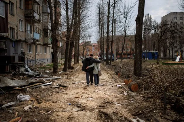 A couple hugs while walking past a building that was heavily damaged by shelling, as Russia's attack on Ukraine continues, in Kharkiv, Ukraine, April 10, 2022. (Photo by Alkis Konstantinidis/Reuters)