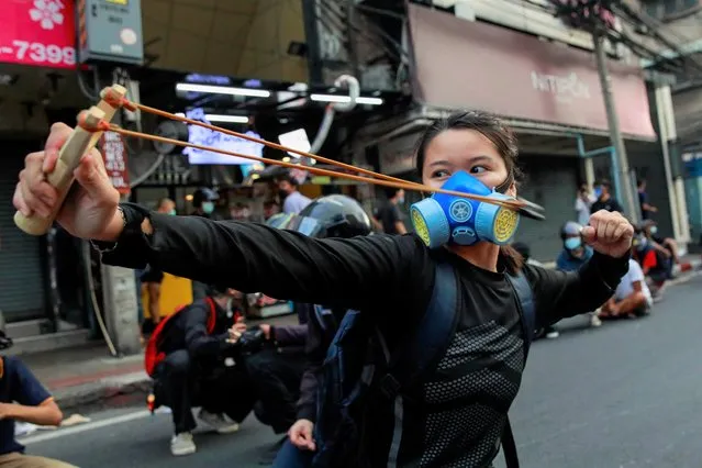 A demonstrator uses a slingshot during clashes with police at a protest against what they call the government's failure in handling the coronavirus disease (COVID-19) outbreak, in Bangkok, Thailand, August 7, 2021. (Photo by Soe Zeya Tun/Reuters)