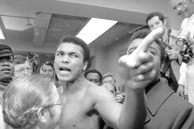 The boxer Muhammad Ali puts on a show at the New York State Athletic Commission's office in New York City on January 23, 1974, as he tries to force his way into the room where his opponent, Joe Frazier, was getting his pre-fight physical. (Photo by Marty Lederhandler/AP Photo)