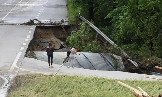 A woman takes pictures of a hole in the federal road 12 near Simbach am Inn, southern Germany, on June 2, 2016 on the day after heavy rains. Five persons were found dead in Germany after heavy rains lashed parts of the country, cutting roads, stranding people on rooftops and forcing schools to close their doors. (Photo by Christof Stache/AFP Photo)