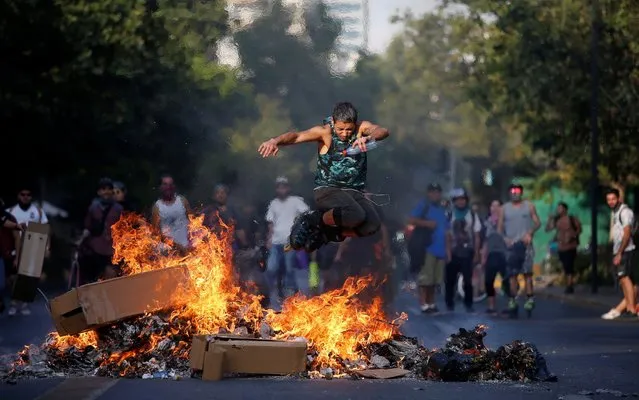 A man wearing roller blades jumps over a burning barricade during protests against Chile's government at the neighbourhood of Providencia in Santiago, Chile on December 6, 2019. (Photo by Ivan Alvarado/Reuters)