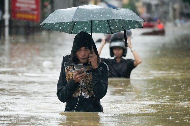 Residents protect their belongings as they negotiate a flooded street caused by heavy rains from Tropical Storm Yagi, locally called Enteng, in Cainta, Rizal province, Philippines, Monday, September 2, 2024. (Photo by Aaron Favila/AP Photo)