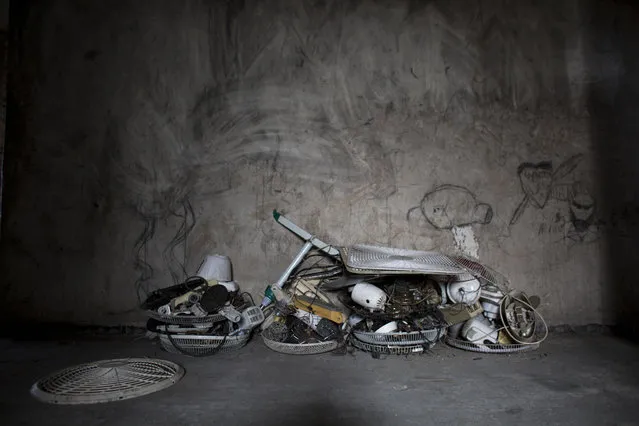 In this June 29, 2015 photo, fan parts recovered by Jimmy Bellefleur sit stacked in the hallway of the abandoned, earthquake damaged government office building where he lives with his family in Port-au-Prince, Haiti. Bellefleur's work as an electrician enables him to buy food and afford relative luxuries such as a double bed and the used televisions and fans he's brought back to life. (Photo by Rebecca Blackwell/AP Photo)