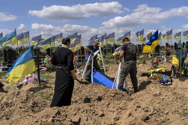 Undertakers lower the coffin of Ukrainian serviceman Oleksander Matyukhin, 32, in Kharkiv, eastern Ukraine, Monday, May 23, 2022. (Photo by Bernat Armangue/AP Photo)