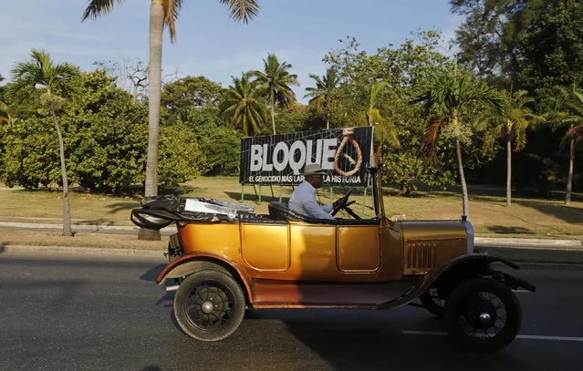 A man drives his vintage car past a billboard with a message that reads in Spanish; “Blockade, the longest genocide in history”, in reference to the U.S. trade embargo imposed on Cuba, in Havana, Cuba, Friday, April 10, 2015. (Photo by Desmond Boylan/AP Photo)