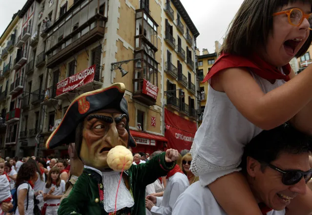 A girl laughs in front of a “cabezudo” (big head) during San Fermin's “Comparsa de gigantes y cabezudos” (Parade of the giants and the big heads) in Pamplona, northern Spain, July 7, 2017. (Photo by Eloy Alonso/Reuters)
