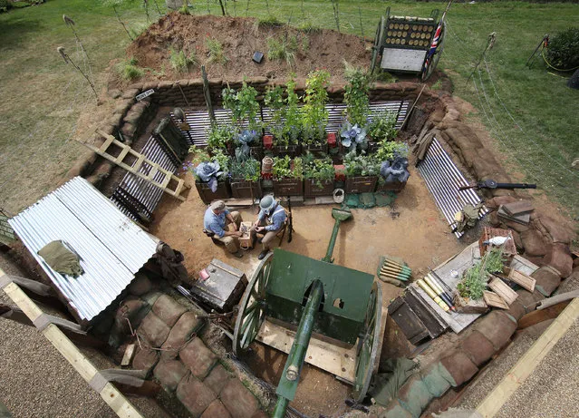 Men dressed as British soldiers sit a garden called “Lest We Forget”, which recreates a First World War trench at the Hampton Court Flower Show on July 7, 2014 in London, England. Hampton Court Palace Flower Show opens to the public tomorrow and runs until July 13, 2014. It is the world's largest flower show with over 600 exhibitors spread over 34 acres. (Photo by Peter Macdiarmid/Getty Images)