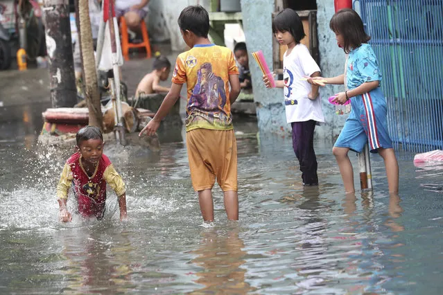 Children play on a flooded street in Jakarta, Indonesia, Sunday, January 5, 2020. Landslides and floods triggered by torrential downpours have left dozens of people dead in and around Indonesia's capital, as rescuers struggled to search for people apparently buried under tons of mud, officials said Saturday. (Photo by Tatan Syuflana/AP Photo)