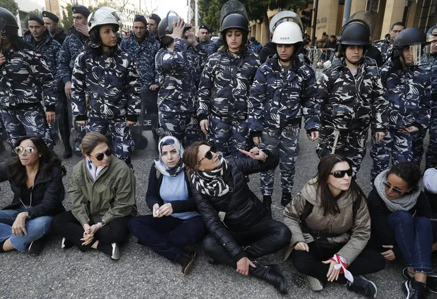 Anti-government protesters sit in the middle of a road in front the riot police as they gather to prevent the Lebanese lawmakers from reaching the parliament building to attend the 2020 budget discussion session, in downtown Beirut, Lebanon, Monday, January 27, 2020. (Photo by Hussein Malla/AP Photo)
