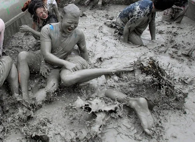Participants play in a mud pool during the Boryeong Mud Festival at Daecheon Beach in Boryeong, South Korea, Friday, July 18, 2014. The 17th annual mud festival features mud wrestling and mud sliding. (Photo by Ahn Young-joon/AP Photo)