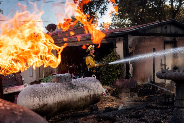 Firefighter Nolan Graham sprays water around a scorched garage as the Boyles fire burns in Clearlake, Calif., on Sunday, September 8, 2024. (Photo by Noah Berger/AP Photo)