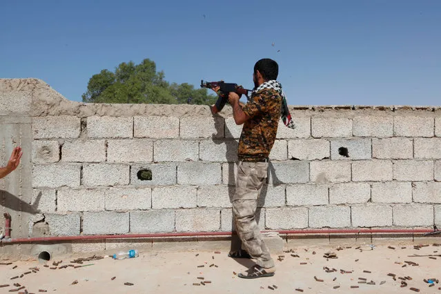 A fighter from forces aligned with Libya's new unity government fires a weapon from atop a house on an Islamic State position in the Zaafran area in Sirte June 30, 2016. (Photo by Ismail Zitouny/Reuters)