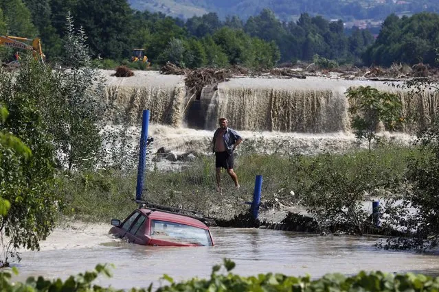 A man looks at a car that is partially submerged in floodwaters in Novaci, southwest Romania, July 30, 2014. Hundreds of people were evacuated from floods in southern Romania, local authorities reported. (Photo by Bogdan Cristel/Reuters)