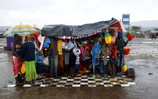 People shelter from heavy rain in a makeshift photo booth where photographers charge clients to take pictures of them during the Maralal Camel Derby, Kenya, August 15, 2015. (Photo by Goran Tomasevic/Reuters)