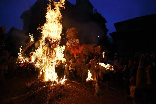 People carry an effigy of the demon Ghantakarna, while another effigy of the demon is burnt to symbolize the destruction of evil, during the Ghantakarna festival in the ancient city of Bhaktapur July 25, 2014. According to local folklore, the demon is believed to “steal” children and women from their homes and localities. (Photo by Navesh Chitrakar/Reuters)