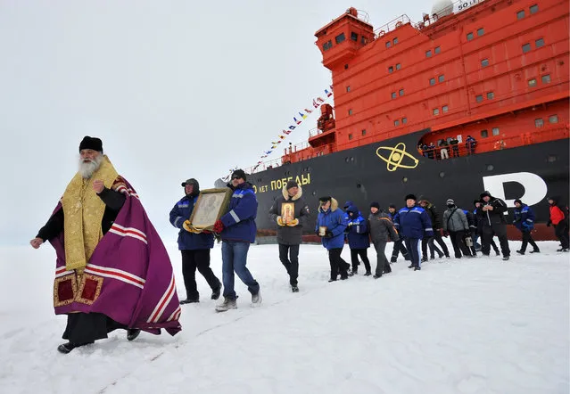 A priest and members of an expedition by a 50 Let Pobedy nuclear-powered icebreaker follow the route of the 1977 North Pole voyage by the Arktika atomic icebreaker at the North Pole, Arctic on August 21, 2017. (Photo by Lev Fedoseyev/TASS)