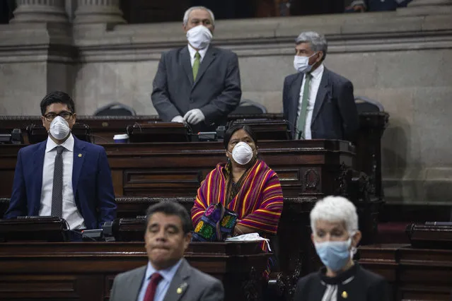 Lawmakers wearing face masks as a precaution against the spread of COVID-19 attend a session in Congress, in Guatemala City, Wednesday, March 18, 2020. Guatemala's President Alejandro Giammattei delivered his emergency economic relief plan spurred by the coronavirus crisis. (Photo by Moises Castillo/AP Photo)