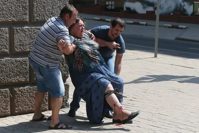 Local men help a wounded woman  after a mortar attack by the Ukrainian army of the center of Donetsk, Ukraine, 14 August 2014. Reports state that ten local people where wounded and one killed after the mortar attack. (Photo by Sergei Ilnitsky/EPA)