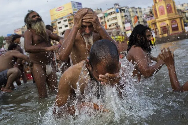 Hindu devotees take a bath in the Godavari River during Kumbh Mela, or Pitcher Festival, in Nasik, India, Saturday, August 29, 2015. Millions of people, most of them devout Hindus from India and across the world and some curious tourists, gather at the Kumbh celebrations spread over several weeks/months. (Photo by Bernat Armangue/AP Photo)