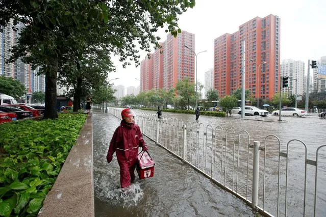 A food deliveryman wades through a flooded street during a heavy rainfall in Shilipu, Chaoyang Road, Beijing, China, July 20, 2016. (Photo by Jason Lee/Reuters)