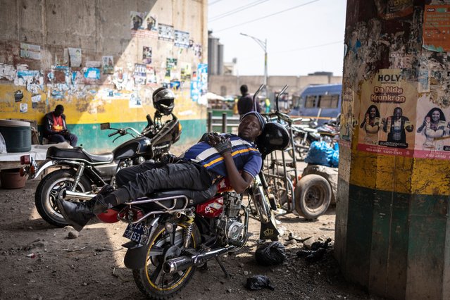 A man naps on a motorbike taxi beneath a bridge in Accra, Ghana on December 9, 2024. (Photo by Olympia de Maismont/AFP Photo)