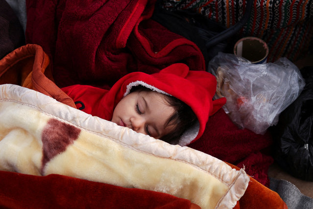 A toddler sleeps while people wait to cross into Lebanon from Syria, at the Masnaa border crossing, Syria on December 12, 2024. (Photo by Amr Alfiky/Reuters)