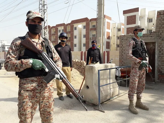 Pakistani security personnel stand guard outside apartments that were converted to a quarantine facility for people suspected of being exposed to the coronavirus after having travelled to Iran, in Sukkar, Pakistan, Tuesday, March 17, 2020. For most people, the new coronavirus causes only mild or moderate symptoms. For some it can cause more severe illness. (Photo by Pervez Khan/AP Photo)