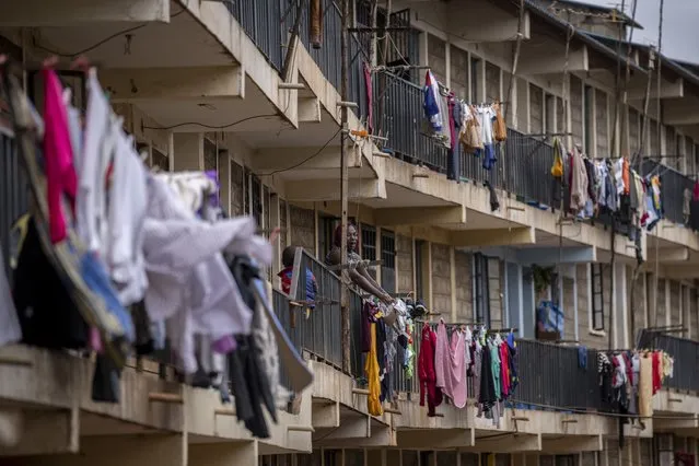 A woman hangs washing to dry on the balcony of an apartment block in the Kibera neighborhood of Nairobi, Kenya Sunday, August 14, 2022. (Photo by Ben Curtis/AP Photo)