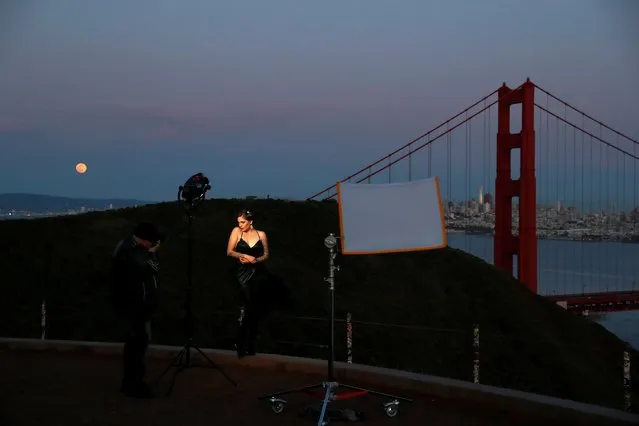 Photographer Jason Lanier takes photographs of model Emily Rinaldo during a fashion shoot as the spread of coronavirus disease (COVID-19) continues, while the Supermoon rises through the clouds at Golden Gate Bridge View Vista Point across from San Francisco, California, U.S., April 7, 2020. (Photo by Shannon Stapleton/Reuters)
