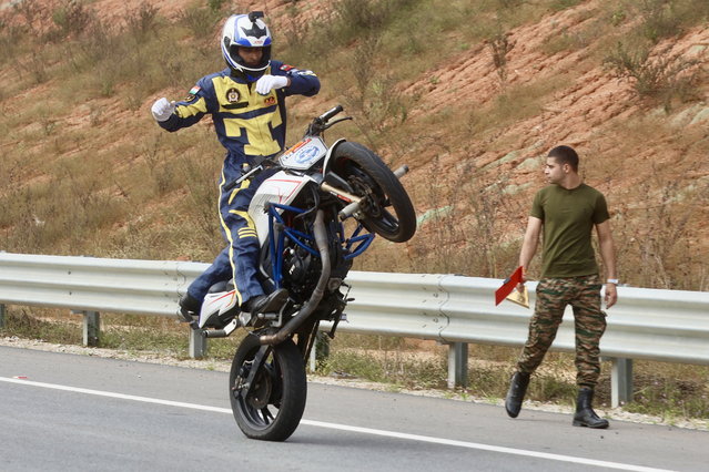 Sumit Tomar, a member of the Indian Army and Army Service Corps (ASC) motorcycle display squad known as the “Tornadoes”, attempts a Guinness World Record for “The longest no-hands motorbike wheelie” held on the outskirts of Bangalore, India, 10 December 2024. Tomar completed a 1,715.4-meter wheelie in 2 minutes and 29 seconds, surpassing the previous record of 918.24 meters held by Elliot Grondahl of Sweden. (Photo by Jagadeesh N.V./EPA)