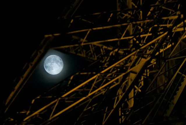 The Supermoon is seen through the Eiffel Tower in Paris. (Photo by Christophe Ena/AP Photo)