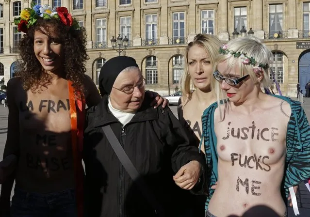 Sister Veronique (2nd L), from the Dominican monastic order, poses with members of women's rights group Femen, who are topless with messages written on their chests, as they stage a protest in front of the Justice Ministry at the Place Vendome in Paris October 15, 2012 against the verdict in the gang-rape of teenage girls' trial. After a four-week trial in Fontenay-sous-Bois near Paris, four of the accused were found guilty of taking part in gang-rapes but 10 were acquitted last week. The sentences were far lighter than those recommended by the state prosecutor, who had called for prison sentences of five to seven years for eight of the men. (Photo by Jacky Naegelen/Reuters)