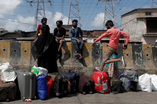 A boy jumps over luggage kept in a line as people wait for transportation to a railway station during an extended lockdown to slow the spread of the coronavirus disease (COVID-19), in Mumbai, India May 28, 2020. (Photo by Francis Mascarenhas/Reuters)